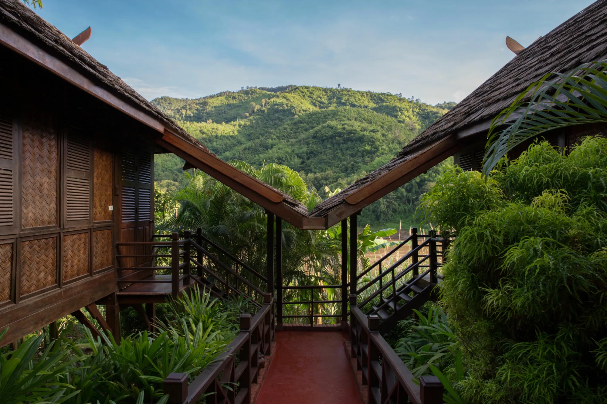 Passerelle longeant les bungalows avec vue sur les collines boisées de l'autre rive